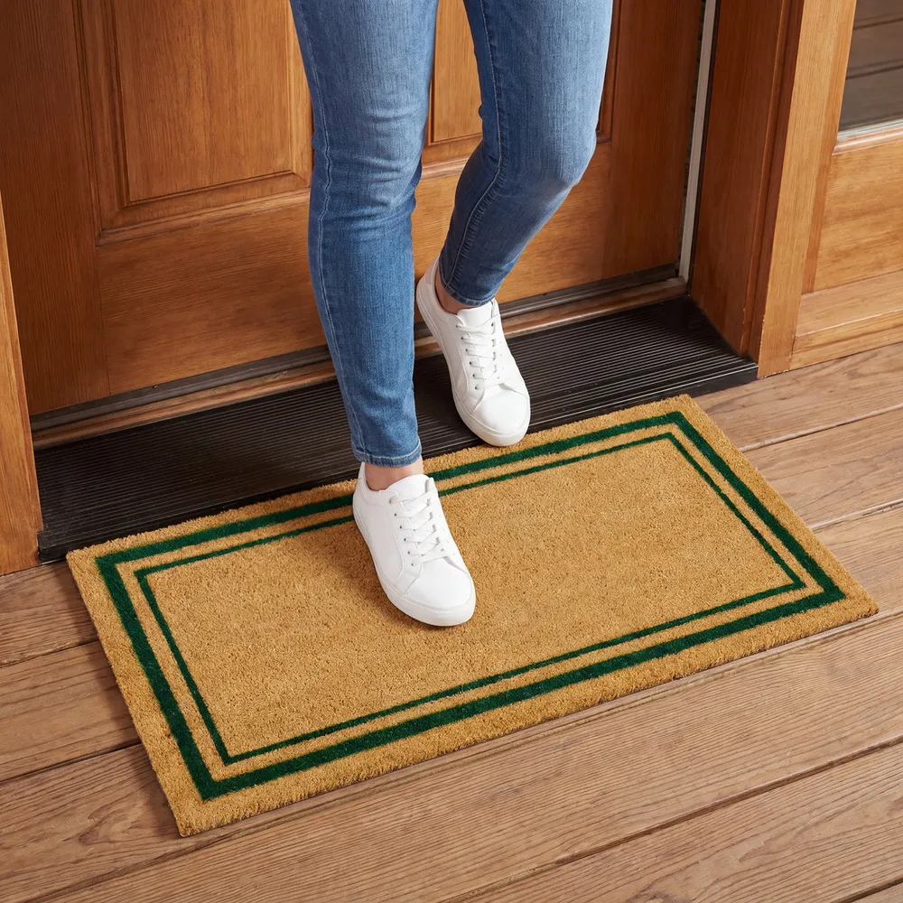 Coir doormat with a green double border at a front door